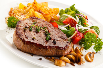 Grilled steak, baked potatoes and vegetable salad on white background 