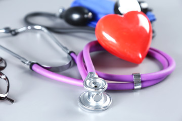 Stethoscope with red heart on light background