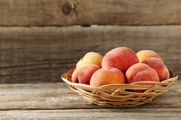 Sweet peach fruit in basket on grey wooden table