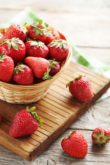 Fresh and tasty strawberries in basket on a grey wooden table