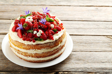 Delicious biscuit cake with berries on grey wooden table