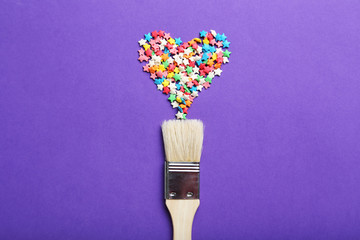 Colorful sprinkles with paintbrush on the purple background