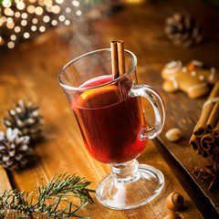 Winter holiday hot alcohol drink. Mulled wine with fruits and spices by Christmas tree.