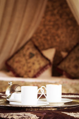 Two turkish coffee cups with oriental canopy bed at the backgrou