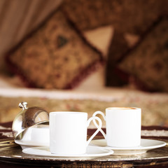 Two turkish coffee cups with oriental canopy bed at the backgrou