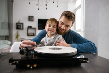 Happy bearded father listening records with his little cute son