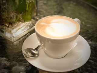 A Cup of hot latte coffee on table with vintage filter.