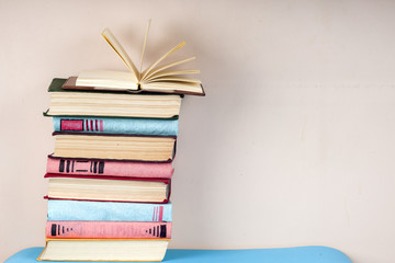 Open book, stack of colorful hardback books on light table. Back to school. Copy space for text