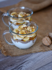 Granola with yogurt, bananas and whole walnuts, maple syrup clea
