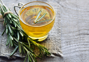 Rosemary herbal tea in a glass cup on rustic wooden background.Selective focus.