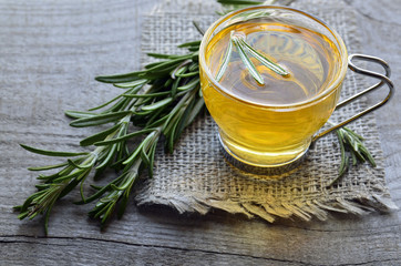 Rosemary herbal tea in a glass cup on rustic wooden background.Selective focus.