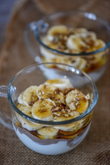 Fototapeta na wymiar Granola with yogurt, bananas and whole walnuts, maple syrup clea