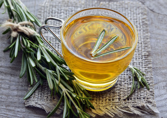 Rosemary herbal tea in a glass cup on rustic wooden background.Selective focus.