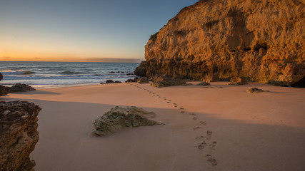 Foot steps coming from the sea at sunrise 