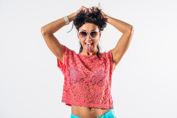 Studio portrait of a playful girl having fun, wearing sunglasses and trendy summer outfit.