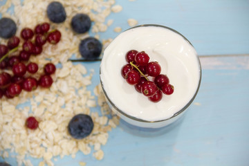 Yogurt with granola and fresh blueberries, in glass bowl over old wood background. Vintage effect.
