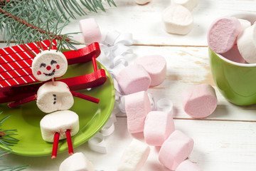 Christmas card with fun marshmallow snowman in green cup, tree