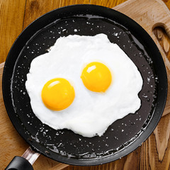 Fried eggs meal in a frying pan for delicious healthy breakfast. Traditional international breakfast food, top view.