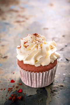 Delicious red velvet cupcake on rusty old metal background. Valentines Day greeting card concept with copy space. Retro style toned.