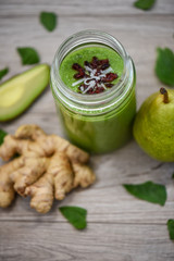 green smoothies in glass with fruits and vegetables on the table
