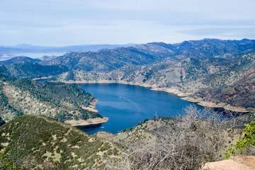 Fototapeta na wymiar Aerial view of Lake Berryessa from the Blue Ridge Trail on a sunny day, featuring the low water levels of the reservoir, and the surrounding blue oak woodland