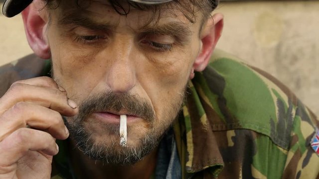 young homeless man smoking in the street: rejected man, drug addict