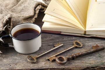 antique book and old keys over rustic wooden background.