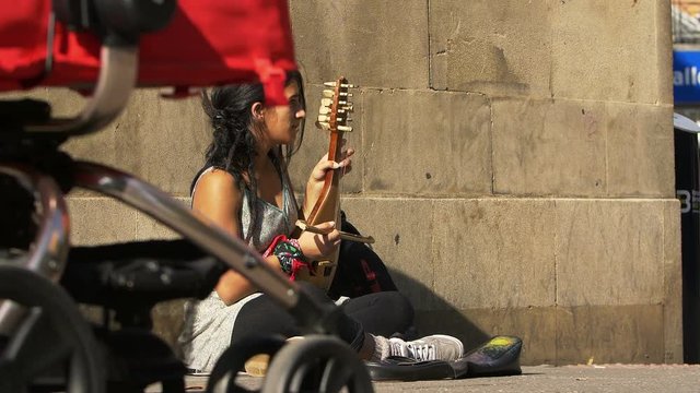 street artist on the sidewalk playing an old string instrument 