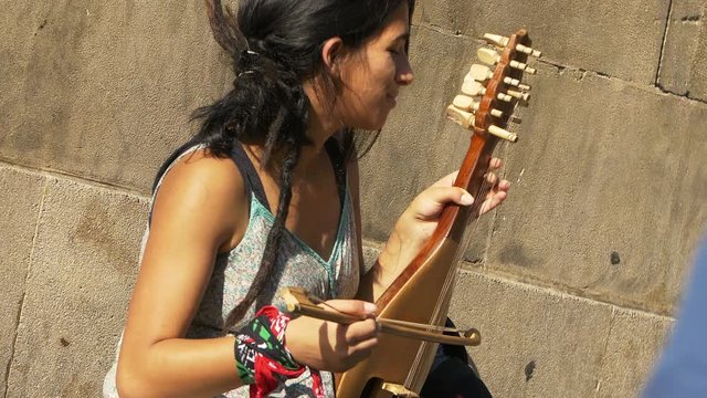 street artist on the sidewalk playing an old string instrument 