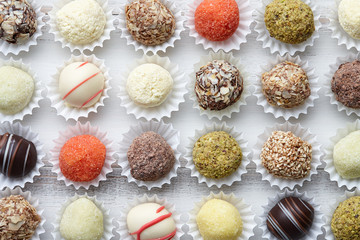 Chocolate truffle candies arranged in rows on white wooden background