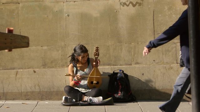 female beggar street artist playing on the sidewalk