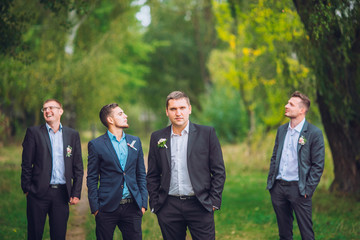 Personable groom with best mans or groomsman posed on park at wedding day.