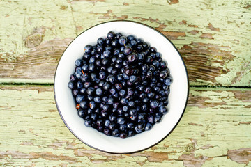 Dish of ripe blueberries on old wooden table