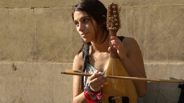young female street artist playing string 