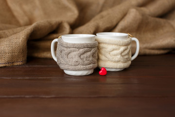 Cups of coffee with knitted cup holder near heart for valentine's day. Love coffee