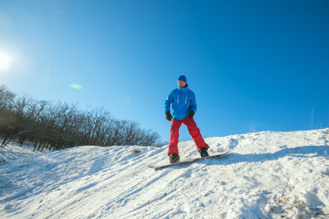 Fototapeta na wymiar Snowboarder is riding downhill in winter forest