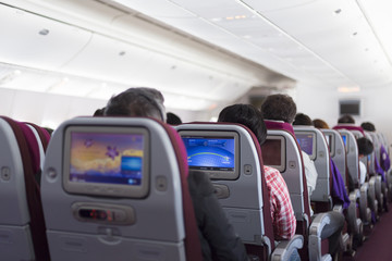 Interior of large passengers airplane with people on seats.