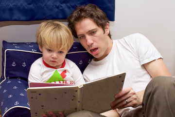 father reading toddler son a bedtime story