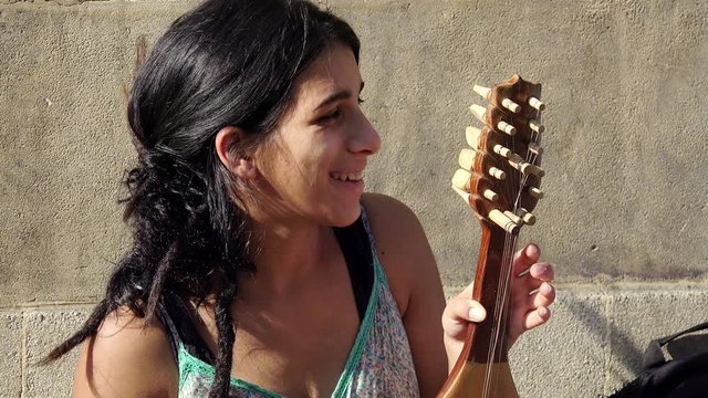 young bulgarian woman playing a string instrument in the street: asking charity