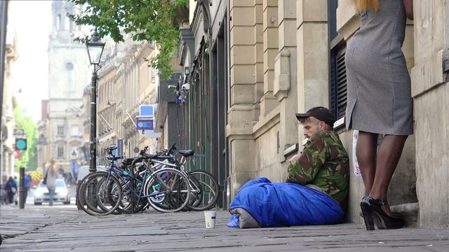 young outcast homeless begging in the street among the passers