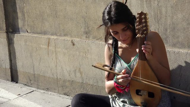young busker plays a rough old string instrument