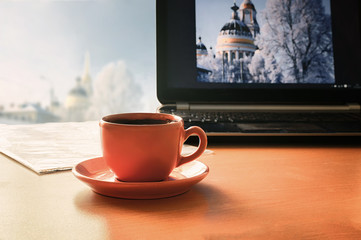 Cozy office setting. Coffee cup on the table in front of the com