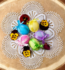 Easter eggs and pansies on wooden (oak) background. Top view, flat lay