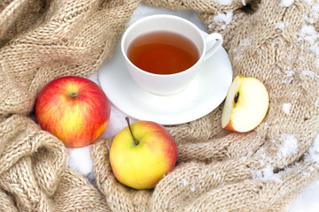 white mug of tea wrapped in a knitted scarf on a saucer with rip