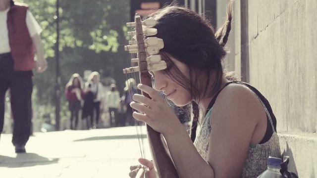 street performer playing sitting on a sidewalk waiting for offers from passers