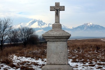 Majestic mountains in the foreground with a stone cross