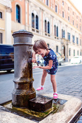 Funny girl drinks water from a fountain in Rome.