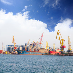 Obraz premium Bright yellow, red and orange cranes and freighters stand in the