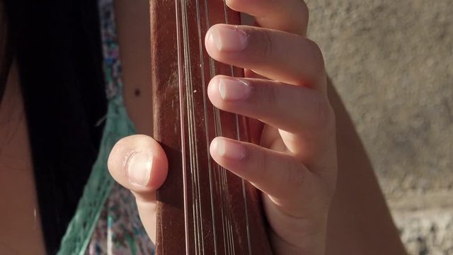 young woman's hands playing a string instrument in the street 