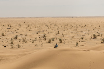 Fototapeta na wymiar Man tourist in desert rub al khali Oman sitting sand view landscape